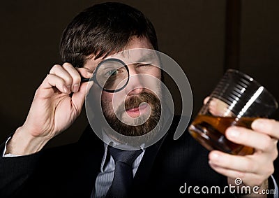 Portrait of handsome young businessman looking at brandy through magnifying glass Stock Photo