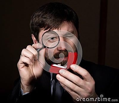 Portrait of handsome young businessman looking at precious ring through magnifying glass Stock Photo