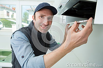 Portrait handyman fixing kitchen exhaust Stock Photo