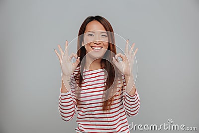 Portrait of a happy asian woman showing ok gesture Stock Photo
