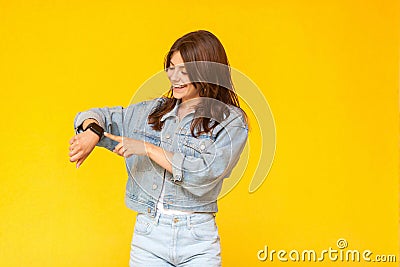 Portrait of happy beautiful brunette young woman in denim casual style standing, toothy smiling, touching and checking her smart Stock Photo
