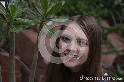 Portrait of happy beautiful young science student. Young girl in a greenhouse with tropic plants Stock Photo
