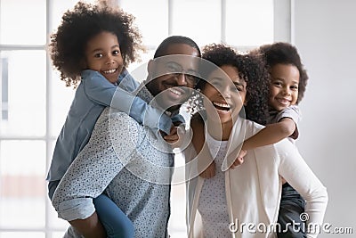 Happy biracial young couple parents giving piggyback ride to kids. Stock Photo