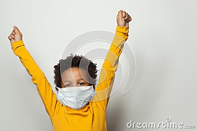 Portrait of happy black child boy in medical protective face mask holding hands up Stock Photo