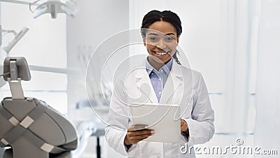 Portrait of happy black female dentist in white coat with digital tablet Stock Photo