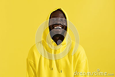 Portrait of happy black man in yellow hoodie on color background Stock Photo
