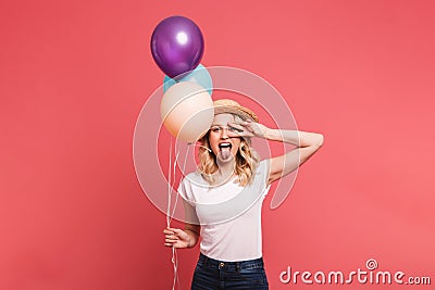 Portrait of happy blond woman 20s wearing straw hat smiling while holding bunch of colorful balloons Stock Photo