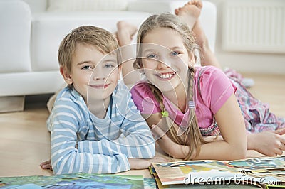 Portrait of happy brother and sister with story books while lying on floor Stock Photo