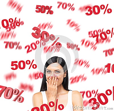 A portrait of a happy brunette lady in a white tank top who is dreaming about discounts. Red percentage marks are flying around th Stock Photo