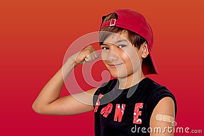 Portrait of happy caucasian boy 9-10 get vaccinated, showing his strong arm with plaster patch after getting covid-19 vaccine inje Stock Photo