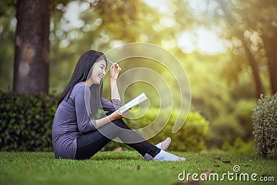 Portrait of happy charming Asian woman reading a book Stock Photo