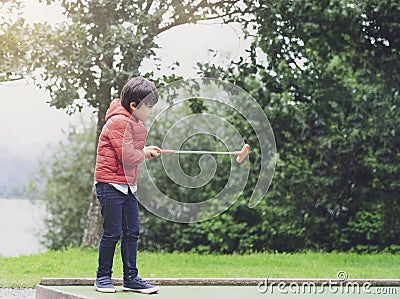 Portrait of Happy child playing mini golf in the park, Active Kid boy playing crazy golf on holiday, Children enjoying his Stock Photo