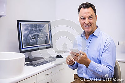 Portrait of happy dentist using mobile phone Stock Photo