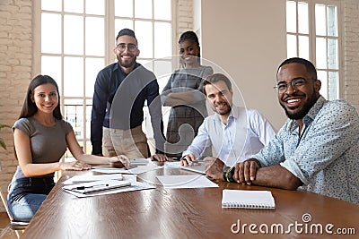 Multiethnic smiling employees gather at boardroom meeting Stock Photo