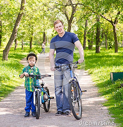 Portrait of a happy family - father and son bicycling in the park Stock Photo