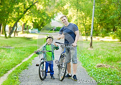 Portrait of a happy family - father and son bicycling in the park Stock Photo