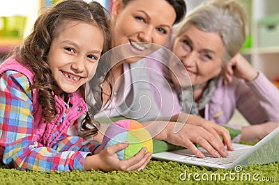 Portrait of happy family with laptop lying on floor Stock Photo