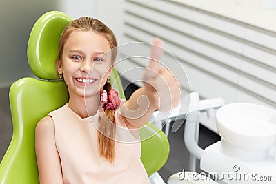 Portrait of happy girl shows thumb up gesture at dental clinic Stock Photo