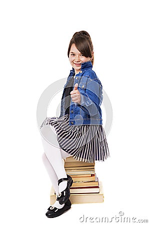 Portrait of a happy girl sitting on a pile of books and showing Stock Photo