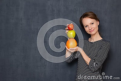 Portrait of happy girl smiling and holding colorful stack of fruits Stock Photo