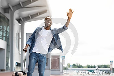 Portrait Of Happy Handsome Black Guy Catching Taxi Near Airport Terminal Stock Photo