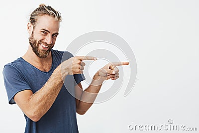 Portrait of happy handsome guy with beard joyfully smiling and pointing aside with index fingers on both hands . Copy Stock Photo