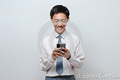Portrait of happy Indonesian Student wearing senior high school uniform smiling looking at phone screen Stock Photo