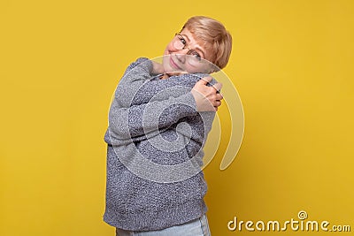 Portrait of happy joyful elderly mature lady embracing herself. Stock Photo