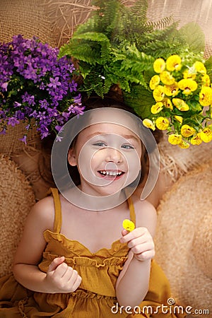 Portrait of a happy little girl lying on background with flowers and straw hat, summer and travel feeling concept Stock Photo