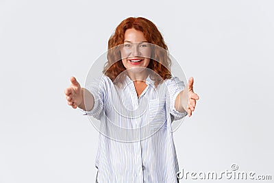 Portrait of happy and lovely redhead middle-aged woman extend hands, reaching arms for hug, mother wanting to cuddle or Stock Photo