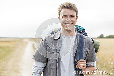 Portrait of happy male hiker with backpack standing on field Stock Photo