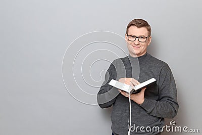 Portrait of happy man holding book in hands and smiling cheerfully Stock Photo