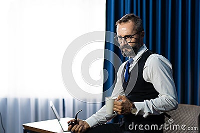 Portrait of happy mature businessman bearded wearing glasses and suite on dark background Stock Photo