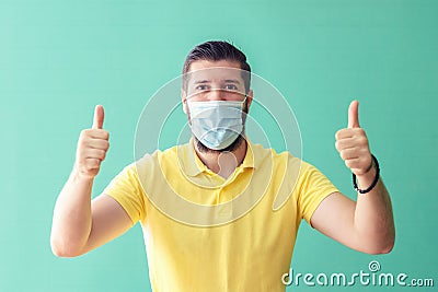 Portrait of happy mature man with protective face mask smiling with thumbs up suggesting safety and prevention for coronavirus Stock Photo