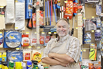 Portrait of a happy mature salesperson with arms crossed in hardware store Editorial Stock Photo