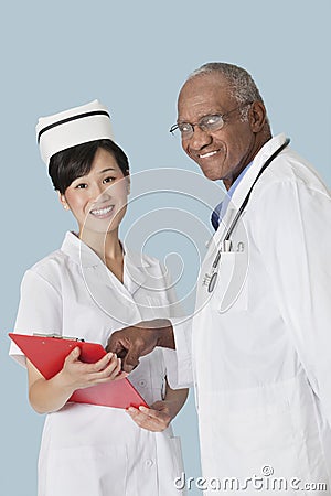 Portrait of happy medical professionals having a discussion over medical report against light blue background Stock Photo