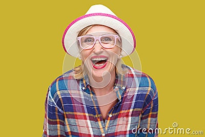 Portrait of happy modern stylish mature woman in casual style with hat and eyeglasses standing and looking at camera with Stock Photo