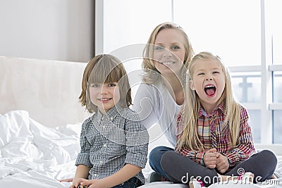 Portrait of happy mother with children in bedroom Stock Photo