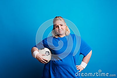 Portrait of a happy overweight woman with a ball in studio on a blue background. Stock Photo