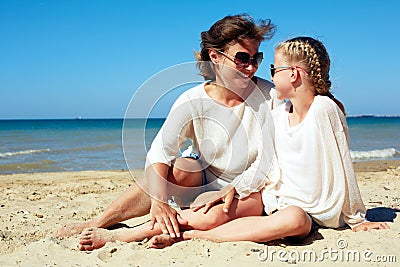 Portrait of a happy parent and child resting on the beach Stock Photo