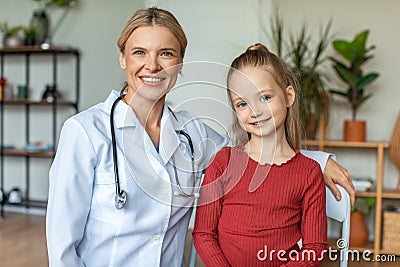 Portrait of happy pediatrician and pretty child girl looking and smiling at camera, sitting in doctor's office Stock Photo