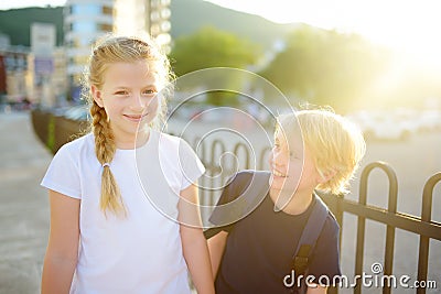 Portrait of a happy preteens girl and boy on a city street during a summer sunset. Friends are walking together. First love Stock Photo