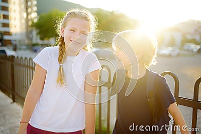 Portrait of a happy preteens girl and boy on a city street during a summer sunset. Friends are walking together. First love Stock Photo