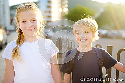 Portrait of a happy preteens girl and boy on a city street during a summer sunset. Friends are walking together Stock Photo