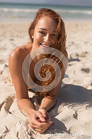 Young Caucasian woman in bikini lying on the sand and looking at camera on the beach Stock Photo