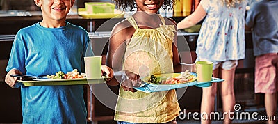 Happy school children holding food tray in canteen Stock Photo