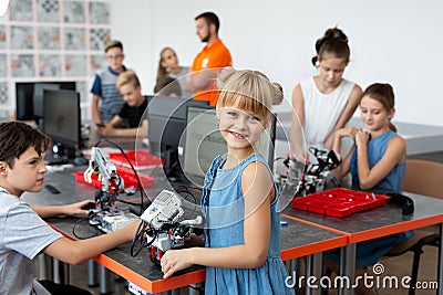 Portrait of a happy schoolgirl girl in a robotics class, she holds a robot assembled from plastic parts programmed on a Stock Photo