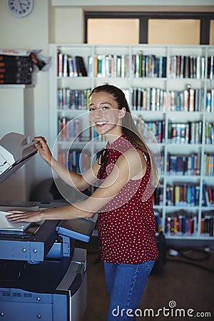 Portrait of happy schoolgirl using Xerox photocopier in library Stock Photo