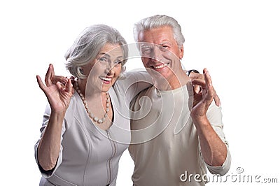 Portrait of happy senior couple showing ok on white background Stock Photo