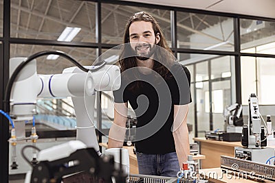 Portrait happy smile engineer male learning education in Industrial Robotics program with robot arm simulation model in university Stock Photo